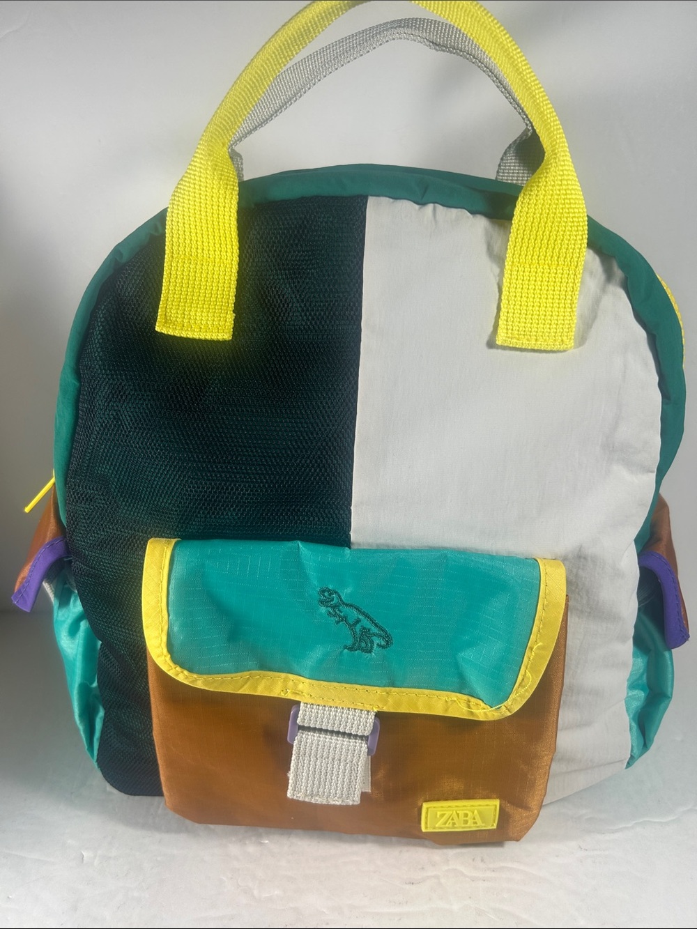 Zara Colorblock Mini Backpack in Teal, Black, Cream & Brown with Yellow Handles.